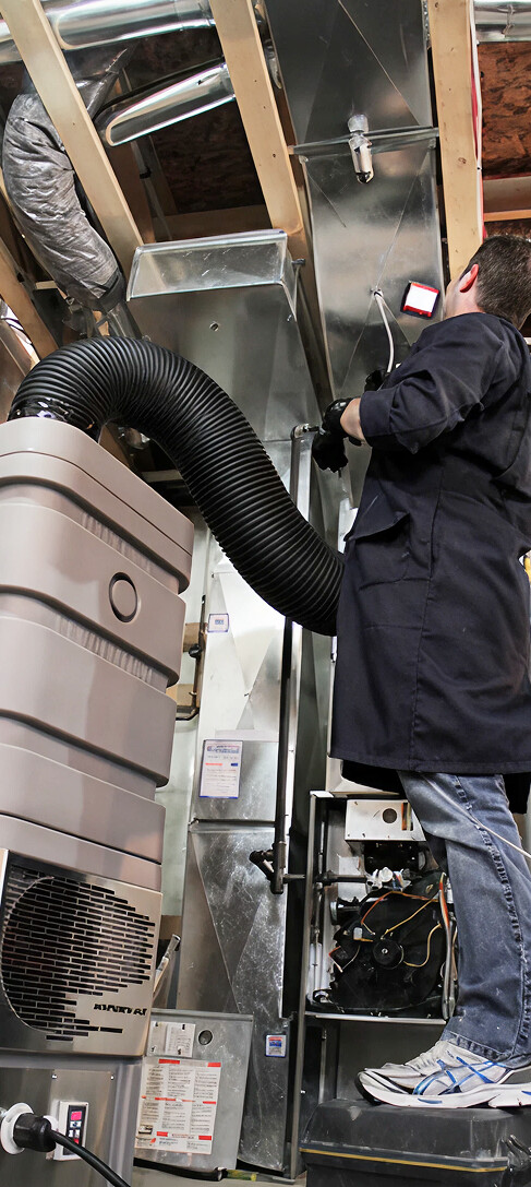 HVAC technician inspecting and cleaning air duct system